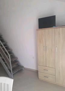 a living room with a tv on a cabinet and a staircase at Elvi Apartment 4 in Rakhónion