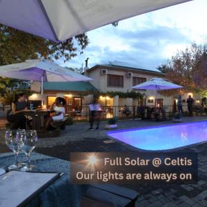a pool with people sitting at tables and umbrellas at Celtis Country Lodge & Restaurant in Middelburg