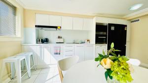 a kitchen with white cabinets and a table with a vase of flowers at Three Monkeys Residence in Kellyville