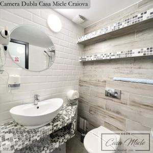 Baño blanco con lavabo y espejo en Casa Micle en Craiova