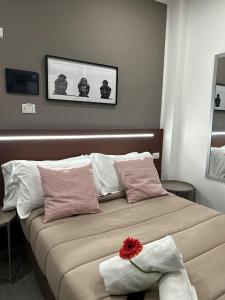 uma cama com almofadas cor-de-rosa e brancas e uma flor vermelha em Crisvan em Bellaria-Igea Marina
