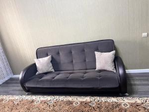 Un sofá negro con dos almohadas en una habitación en ЖК Алмалы, напротив Алматы Арены 81-90 en Almaty