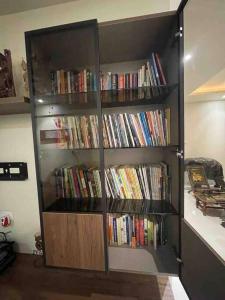 una estantería llena de libros en una habitación en Endora homestay - A fully equipped lake-facing 3BHK en Lavasa