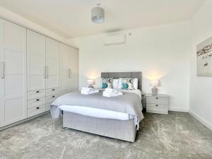 a white bedroom with a bed and two night stands at Shoreside Villa, by the Golf Course in Bridlington
