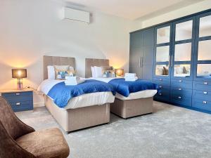 two beds in a bedroom with blue cabinets at Shoreside Villa, by the Golf Course in Bridlington