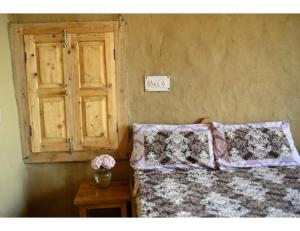 a bedroom with a bed and a window and a table at Chalo Daanda Forest Farm, Chamba in Chamba