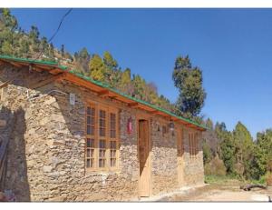 a stone building with wooden doors on the side of it at Chalo Daanda Forest Farm, Chamba in Chamba