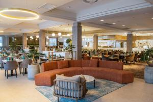 a hotel lobby with a couch and a restaurant at Hotel Azur Siofok in Siófok