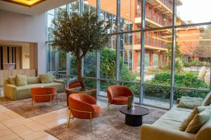 un vestíbulo con muebles y un árbol en un edificio en Hotel Azur Siofok en Siófok