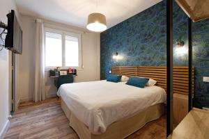 1 dormitorio con 1 cama grande y pared azul en Contact Hôtel du Commerce et son restaurant Côte à Côte, en Autun