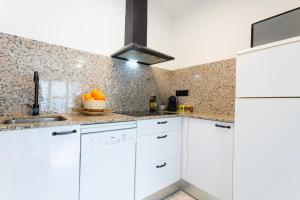 a kitchen with white cabinets and a tile wall at CORAL 14 in Llafranc +6 photos