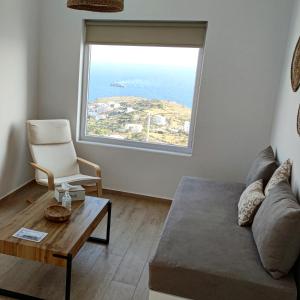 sala de estar con sofá, silla y ventana grande en Eolia luxury houses Andros, en Batsi