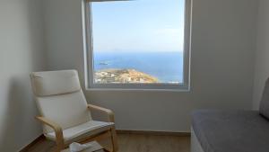 Una silla blanca en una habitación con ventana en Eolia luxury houses Andros, en Batsi