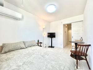 a bedroom with a bed and a table and a television at YIAN-Kamiochiai house in Tokyo