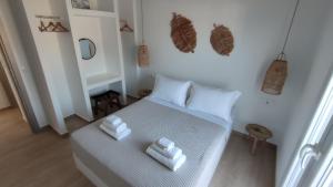 1 dormitorio con 1 cama blanca y 2 toallas en Eolia luxury houses Andros, en Batsi