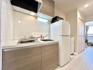 a kitchen with a white refrigerator and a sink at YIAN-Kamiochiai house in Tokyo