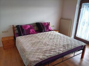 Schlafzimmer mit einem Bett mit rosa Kissen und einem Fenster in der Unterkunft Apartment Bamboleo in Veringendorf
