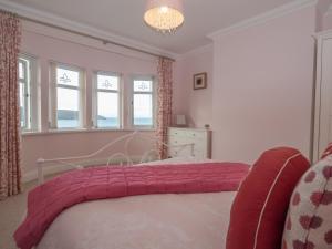 a bedroom with a bed and two windows and a chandelier at High Cliff Gwbert in Towyn