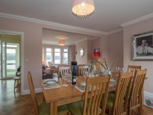 a dining room and living room with a table and chairs at High Cliff Gwbert in Towyn
