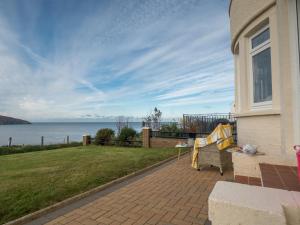 a house with a couch on a patio with a view of the water at High Cliff Gwbert in Towyn