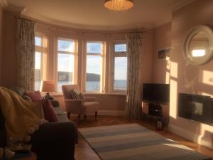 a living room with a couch and a tv and windows at High Cliff Gwbert in Towyn