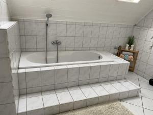 a bath tub in a white tiled bathroom at Ferienwohnung Rosch in Konz