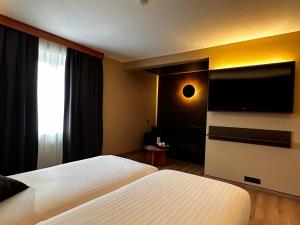 een hotelkamer met 2 bedden en een flatscreen-tv bij Hotel Melba in Bastenaken