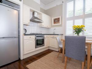 a kitchen with white cabinets and a table and a refrigerator at Pass the Keys High Spec 2 Bedroom Apartment with a View in Great Malvern