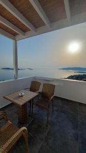 un patio con mesa, sillas y el océano en Eolia luxury houses Andros, en Batsi