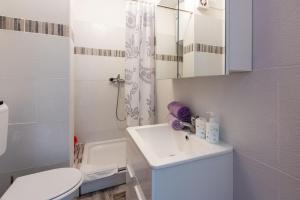 a white bathroom with a sink and a toilet at Apartments Davor in Banjole