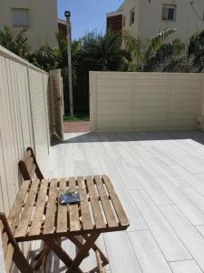 a wooden bench sitting on a patio next to a fence at סוויטת מלכת המפרץ אילת in Eilat