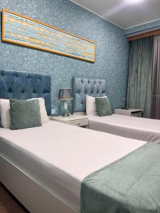 2 Betten in einem Zimmer mit blauen Wänden in der Unterkunft Address Boutique Hotel Baku in Baku