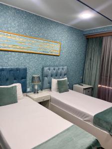 Address Boutique Hotel Baku في باكو: سريرين في غرفة بجدران زرقاء