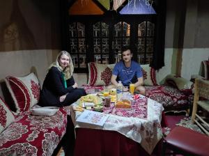 Un uomo e una donna seduti a un tavolo con del cibo di Kasbah Of Peace & Boutique a Zagora