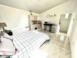 ein weißes Schlafzimmer mit einem Bett und einer Küche in der Unterkunft Eagles Rest Cottage in Margate