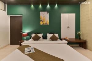 Un dormitorio con dos camas y una pared verde. en EKO STAY- Villa BLANCO, en Lonavala