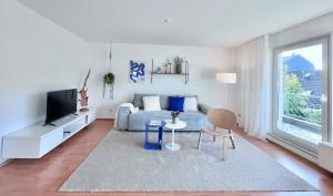 een woonkamer met een blauwe bank en een tv bij TIMELESS APARTMENT: FREE PARKING + BALCONY in Wuppertal