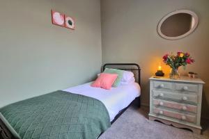 a bedroom with a bed and a dresser with a vase of flowers at Jasper's by Spires Accommodation a great base to stay for Alton Towers and corporate clientele working away from home in Stoke on Trent