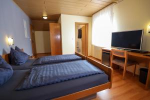 two beds in a room with a desk and a television at Hotel Garni KAMBEITZ in Ötigheim