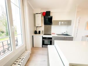 a kitchen with white appliances and a large window at Bel appartement à 10 minutes de Disney in Quincy-Voisins