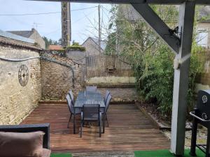 une terrasse en bois avec une table et des chaises. dans l'établissement Le clos de la rose trémière, 