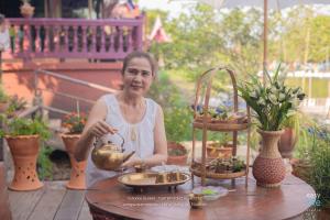 a woman is sitting at a table with plants at ทับทิมทอง โฮมสเตย์ in Ban Khlong Khut