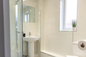 a white bathroom with a sink and a shower at Dubbie House in Leven-Fife