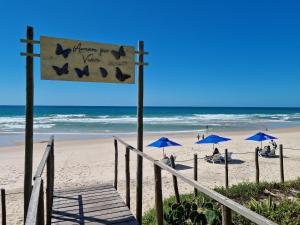 a beach with blue umbrellas and people on the beach at Areias do Mar ! Confortável e com Ar na Sala A315 in Barra de São Miguel
