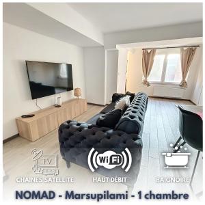 sala de estar con sofá de cuero negro y TV de pantalla plana en NOMAD APARTMENTS - Henin, en Charleroi