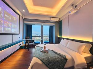 Habitación de hotel con cama grande y pantalla de proyección en Guangzhou Xing Yi International Apartment Hotel - Vertical City Branch, en Guangzhou