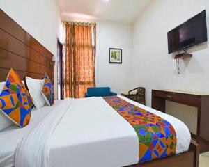Un dormitorio con una cama grande y un televisor de pantalla plana. en FabHotel Jaipur Casa, en Jaipur