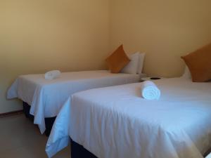 una habitación con dos camas con sábanas blancas en Sweet home guesthouse, en Mthatha