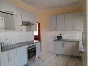 a kitchen with white cabinets and a microwave at Sweet home guesthouse in Mthatha