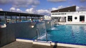 ein Pool mit blauem Wasser in einem Gebäude in der Unterkunft de Leuchtviol in Dorum Neufeld